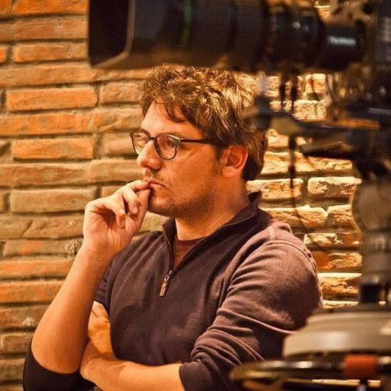 Luca sul set di Beati voi, pensieroso, tra una telecamera e un muro di mattoni